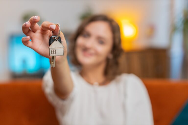 Mulher segurando uma chave com chaveiro de casa, simbolizando a compra de um imóvel e a importância de obter certidões obrigatórias na negociação.